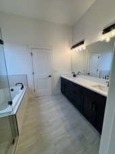 Bathroom with tile patterned floors, vanity, a textured ceiling, and tiled tub