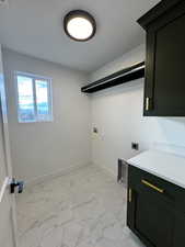 Laundry area with electric dryer hookup, hookup for a washing machine, cabinets, and a textured ceiling