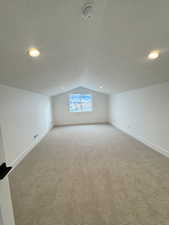 Large Bonus Room Additional living space featuring light carpet, a textured ceiling, and vaulted ceiling