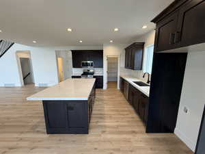 Kitchen with sink, a center island, tasteful backsplash, appliances with stainless steel finishes, and light wood-type flooring