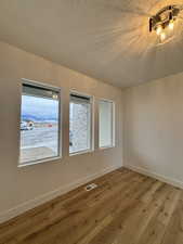 Empty room featuring hardwood / wood-style flooring, a mountain view, and a textured ceiling