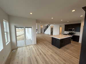 Kitchen featuring a center island, light wood-type flooring, appliances with stainless steel finishes, and tasteful backsplash