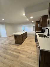 Kitchen with a center island, sink, light wood-type flooring, a textured ceiling, and stainless steel appliances