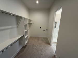 Primary Spacious closet featuring carpet and stackable washer dryer hookups for main level laudry