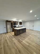 Kitchen featuring a kitchen island, dark brown cabinetry, appliances with stainless steel finishes, and light hardwood / wood-style flooring