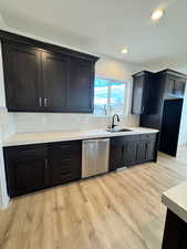 Kitchen with backsplash, dishwasher, sink, and light hardwood / wood-style flooring