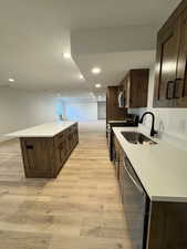 Kitchen with a textured ceiling, sink, light wood-type flooring, and stainless steel appliances