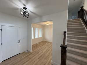 Foyer entrance featuring a chandelier, a textured ceiling, and light hardwood / wood-style flooring