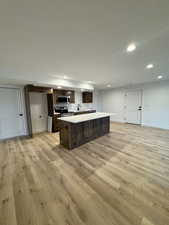 Kitchen with appliances with stainless steel finishes, light hardwood / wood-style floors, and a kitchen island