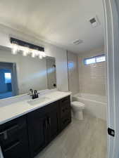 Full bathroom with tiled shower / bath combo, a healthy amount of sunlight, toilet, and vanity