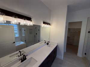 Primary Bathroom featuring tile patterned floors, vanity, and separate shower and tub