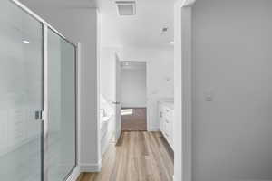 Bathroom with hardwood / wood-style floors, vanity, and independent shower and bath