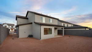 Back house at dusk with a patio and central AC