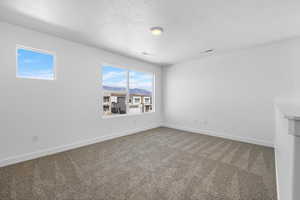 Empty room with carpet flooring and a textured ceiling