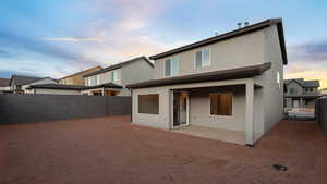 Back house at dusk featuring a patio