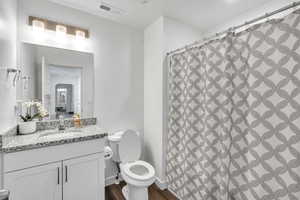 Bathroom featuring hardwood / wood-style flooring, vanity, curtained shower, and toilet