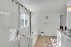 Bathroom with tile patterned floors, vanity, plus walk in shower, and a textured ceiling