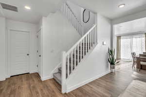 Stairway featuring a textured ceiling and hardwood / wood-style flooring