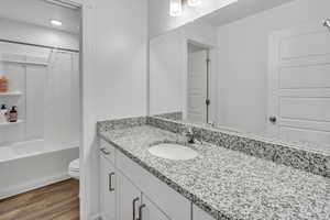 Full bathroom featuring hardwood / wood-style floors, vanity, shower / tub combo, and toilet