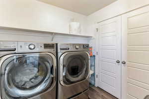 Laundry room with separate washer and dryer and dark hardwood / wood-style flooring