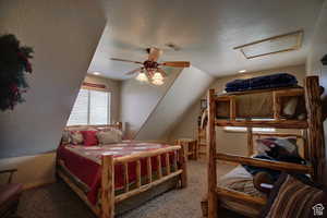 Carpeted bedroom with a textured ceiling, ceiling fan, and lofted ceiling