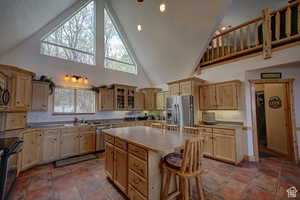 Kitchen with a kitchen bar, a center island, high vaulted ceiling, and black appliances