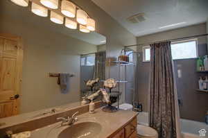 Full bathroom featuring vanity, shower / bathtub combination with curtain, and toilet