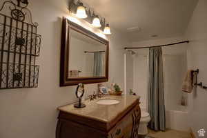 Full bathroom featuring a textured ceiling, vanity, toilet, and shower / bath combo