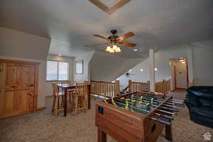 Recreation room with light carpet, ceiling fan, and a textured ceiling