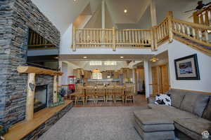 Large open great  room with ceiling fan, a fireplace, and high vaulted ceiling