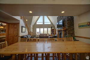 Dining space featuring ceiling fan, a fireplace, and high vaulted ceiling