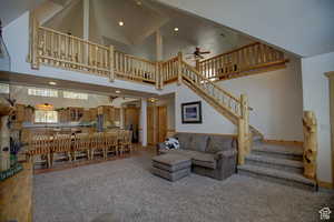 Living room featuring carpet, ceiling fan, and high vaulted ceiling