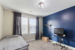 Bedroom with light carpet, a textured ceiling, and multiple windows