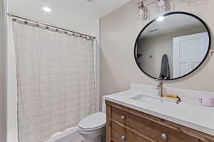 Bathroom with a shower with shower curtain, vanity, and toilet