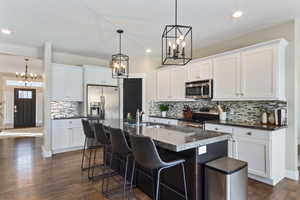 Kitchen with a center island with sink, white cabinets, sink, dark hardwood / wood-style flooring, and stainless steel appliances