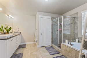 Bathroom with a textured ceiling, vanity, tile patterned floors, and separate shower and tub