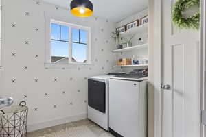 Laundry area featuring light tile patterned floors and washer and clothes dryer