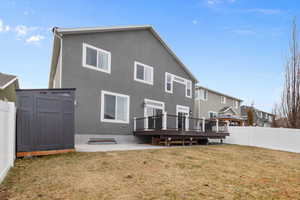 Back of property with a wooden deck, a patio area, a yard, and a shed