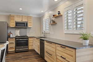 Kitchen featuring sink, stainless steel appliances, dark hardwood / wood-style floors, light brown cabinetry, and ornamental molding