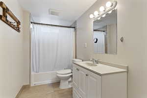 Full bathroom featuring tile patterned floors, shower / bathtub combination with curtain, vanity, and toilet