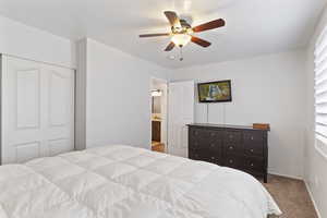 Bedroom with ceiling fan, light carpet, and a closet