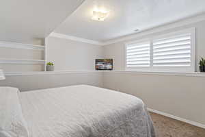 Bedroom featuring carpet flooring, a textured ceiling, and ornamental molding