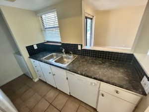 Kitchen featuring white cabinetry, sink, dishwasher, decorative backsplash, and light tile patterned floors