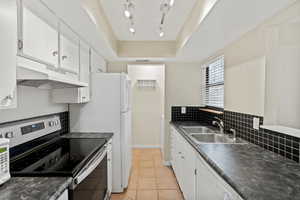 Kitchen with sink, backsplash, a tray ceiling, white cabinets, and stainless steel range with electric cooktop