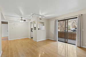 Unfurnished living room featuring track lighting, ceiling fan, and light hardwood / wood-style flooring