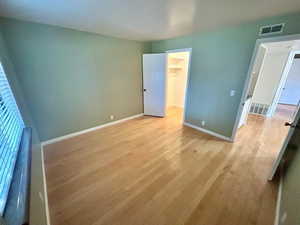 Unfurnished bedroom with light wood-type flooring, a spacious closet, and a closet