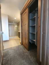 Closet Corridor to bathroom with carpet to tile flooring