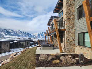 Yard layered in snow featuring a mountain view, a balcony, and a patio