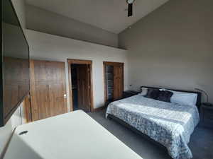 Carpeted bedroom featuring ceiling fan and high vaulted ceiling