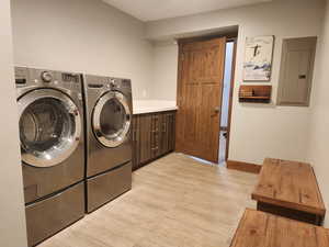 Laundry room with electric panel, cabinets, and washer and dryer